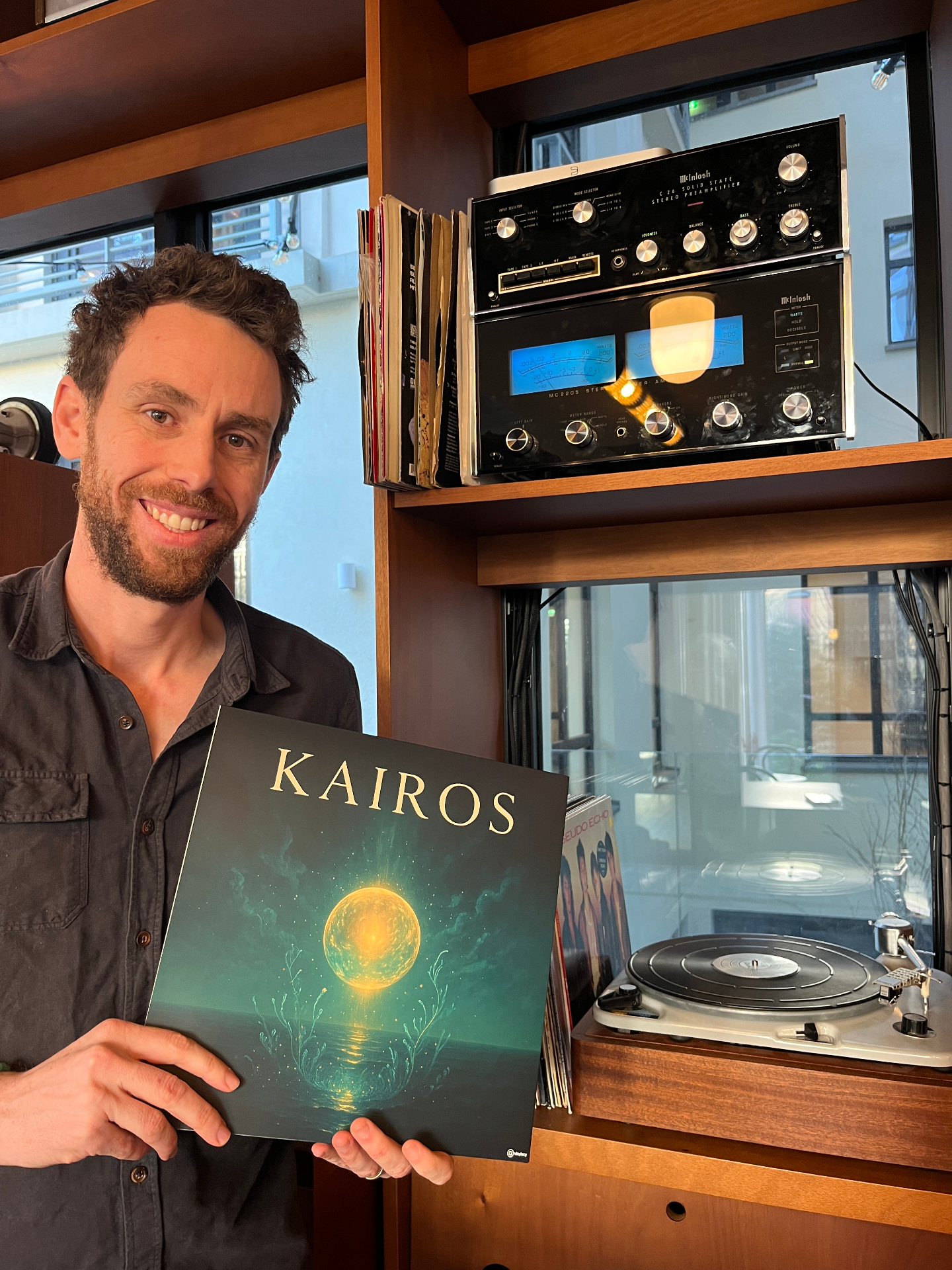 Alwin tenant le vinyle de l'album Kairos devant une platine vintage